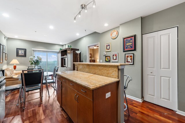 kitchen featuring a breakfast bar area, a kitchen island, and dark hardwood / wood-style flooring