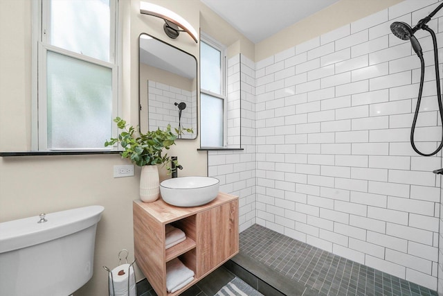 bathroom with vanity, toilet, and tiled shower