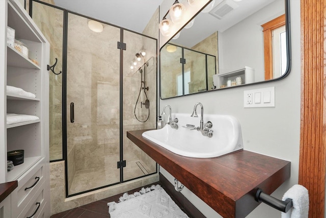 bathroom featuring a shower with door and sink