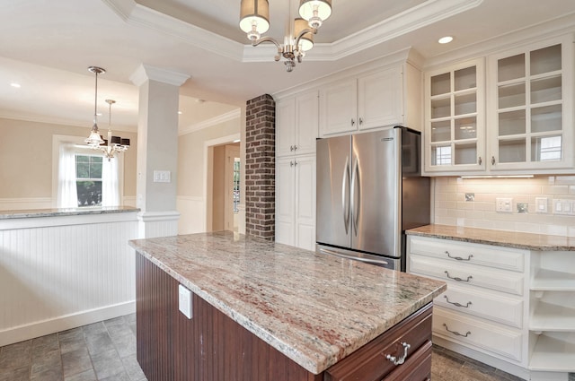 kitchen with stainless steel fridge, tasteful backsplash, hanging light fixtures, white cabinetry, and crown molding