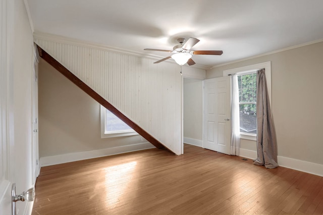 empty room featuring a wealth of natural light, crown molding, and light wood-type flooring