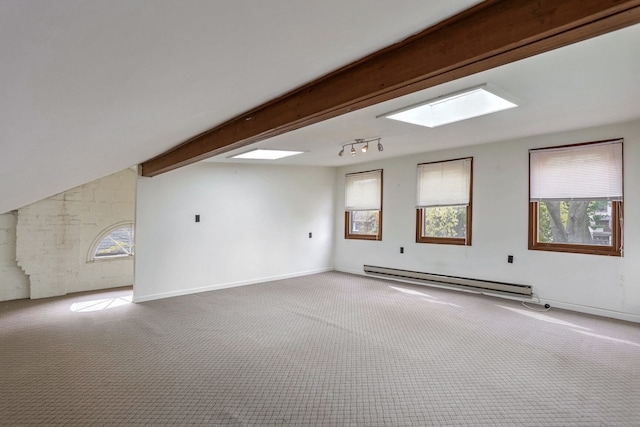 additional living space with a baseboard radiator, vaulted ceiling with skylight, and carpet flooring