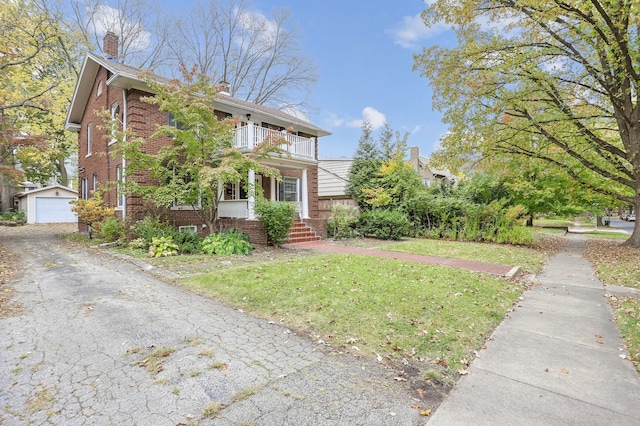 view of side of home featuring an outdoor structure, a yard, a balcony, covered porch, and a garage