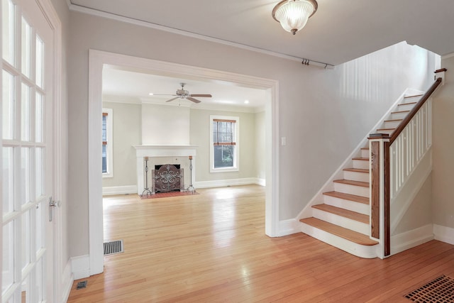 unfurnished living room with light hardwood / wood-style floors, ornamental molding, and ceiling fan