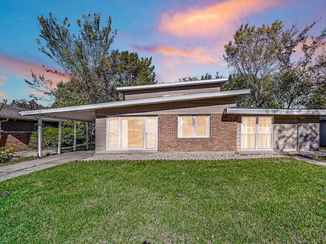 back house at dusk featuring a yard and a carport