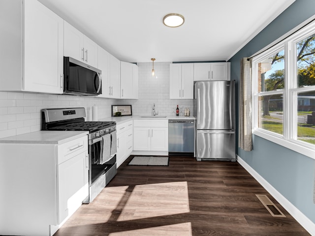 kitchen featuring tasteful backsplash, appliances with stainless steel finishes, sink, dark hardwood / wood-style flooring, and white cabinets