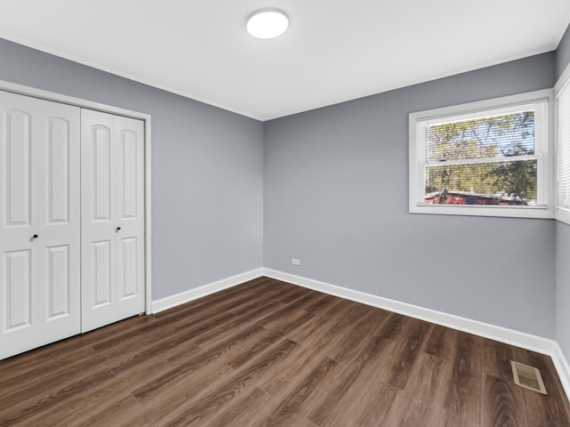 unfurnished bedroom featuring dark wood-type flooring and a closet