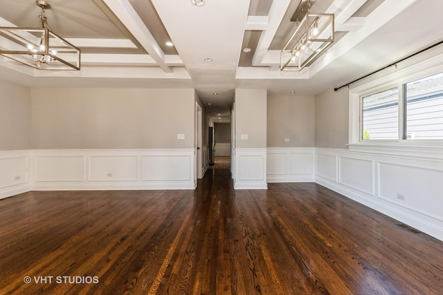 empty room featuring beam ceiling, dark hardwood / wood-style flooring, a notable chandelier, and coffered ceiling