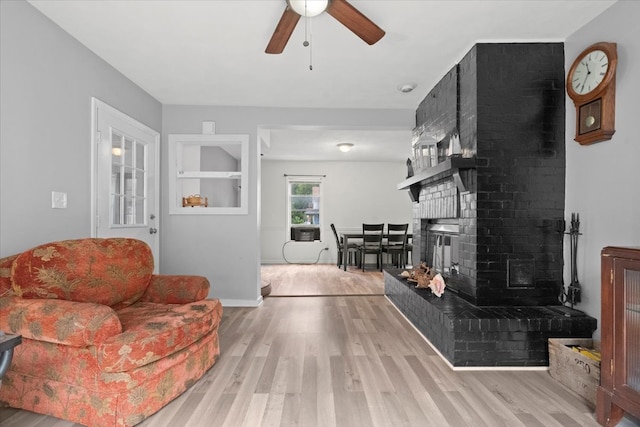 living room featuring a fireplace, ceiling fan, and light hardwood / wood-style floors