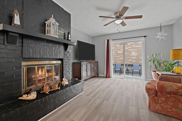 living room with a fireplace, light wood-type flooring, and ceiling fan