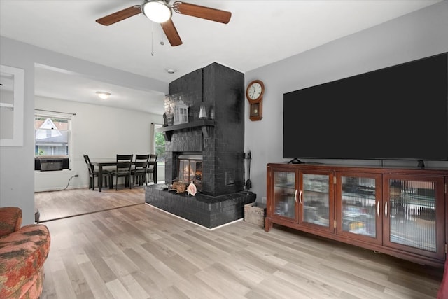 living room with ceiling fan, cooling unit, a fireplace, and light hardwood / wood-style floors