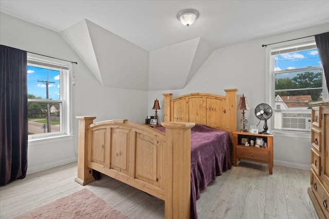 bedroom featuring lofted ceiling, light hardwood / wood-style flooring, and multiple windows