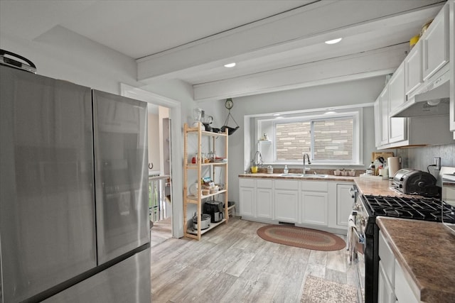 kitchen with beam ceiling, white cabinetry, sink, and stainless steel appliances