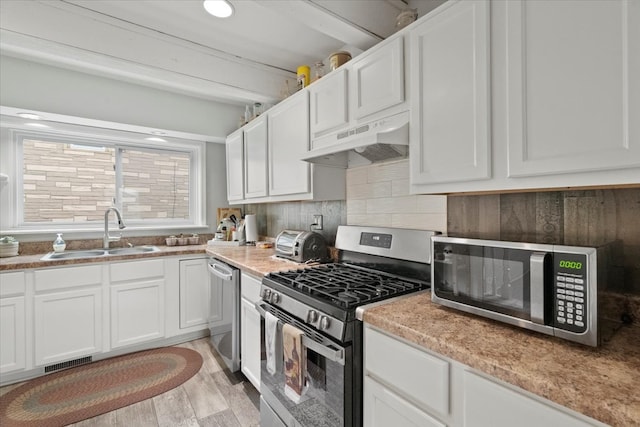 kitchen featuring white cabinets, stainless steel appliances, light wood-type flooring, and sink