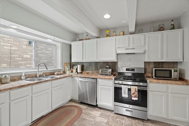 kitchen featuring appliances with stainless steel finishes, beamed ceiling, and white cabinets