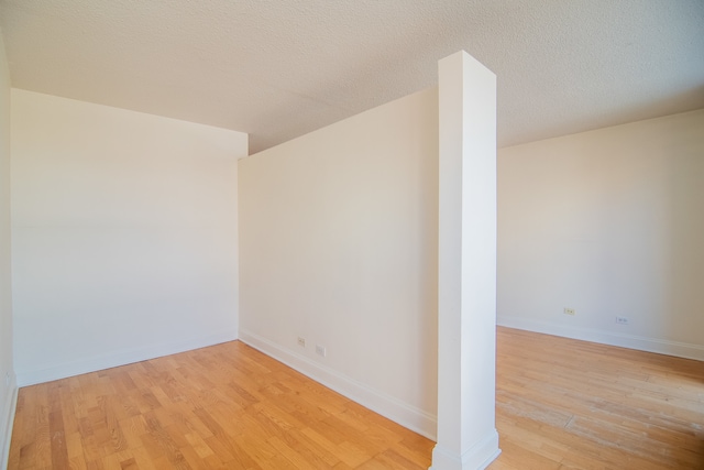 empty room with a textured ceiling and light hardwood / wood-style floors