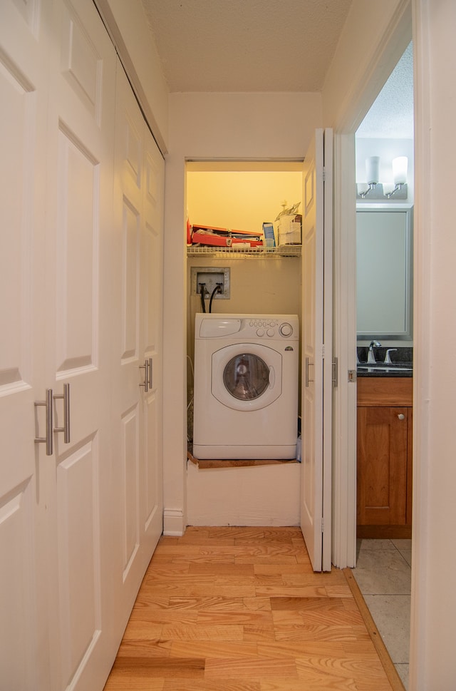 laundry room with light hardwood / wood-style floors, washer / clothes dryer, and sink