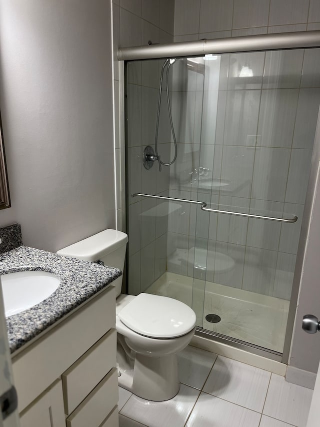 bathroom with tile patterned floors, vanity, a shower with door, and toilet