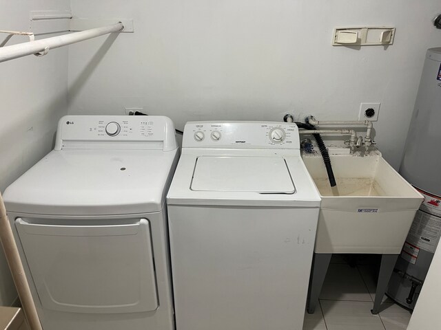 washroom with washing machine and dryer, tile patterned flooring, water heater, and sink