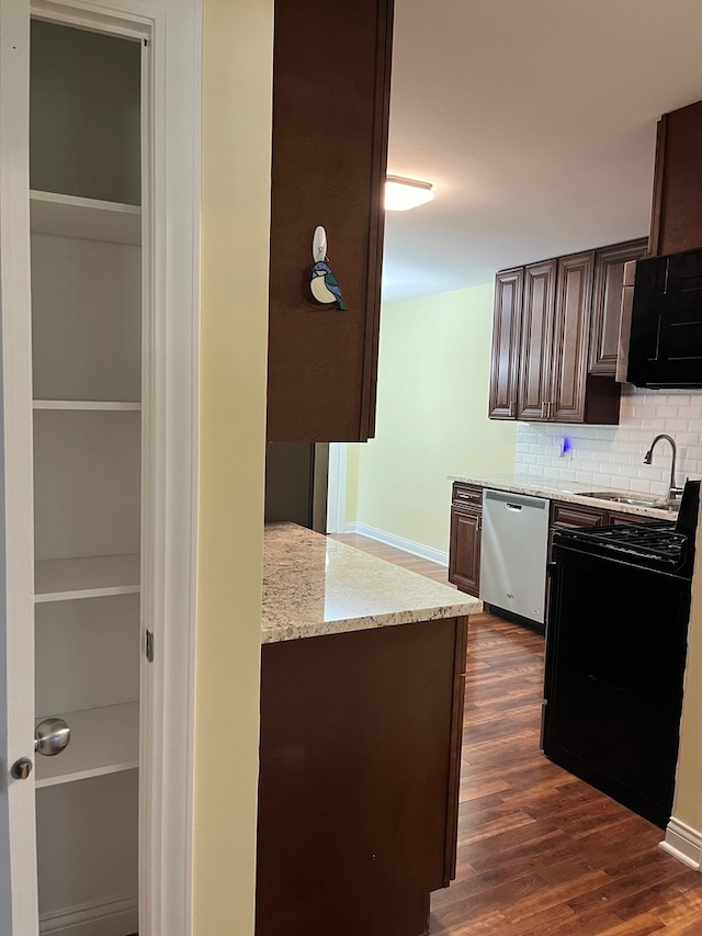 kitchen featuring sink, tasteful backsplash, stainless steel dishwasher, dark hardwood / wood-style floors, and light stone countertops