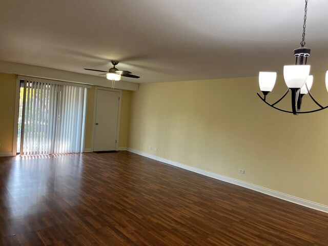 empty room with ceiling fan with notable chandelier and dark hardwood / wood-style flooring