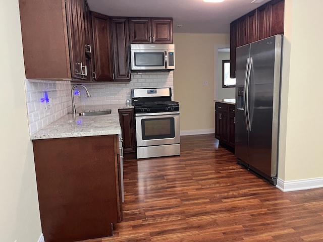 kitchen with stainless steel appliances, dark brown cabinets, dark hardwood / wood-style flooring, and sink