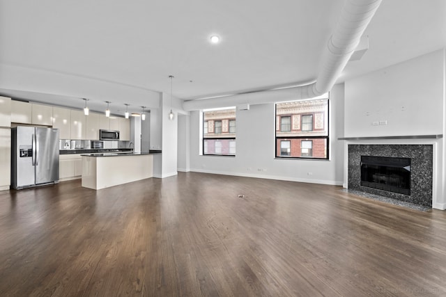 unfurnished living room featuring dark hardwood / wood-style flooring and a tiled fireplace