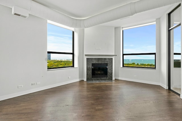 unfurnished living room featuring a wealth of natural light and dark hardwood / wood-style floors