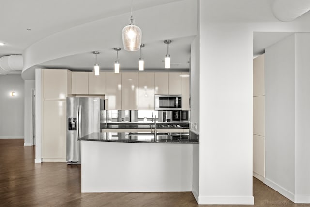 kitchen with dark hardwood / wood-style flooring, dark stone countertops, hanging light fixtures, white cabinets, and appliances with stainless steel finishes