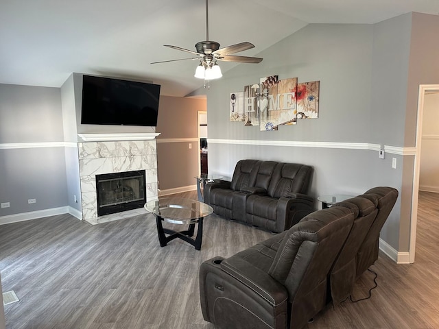 living room featuring wood-type flooring, a tiled fireplace, vaulted ceiling, and ceiling fan