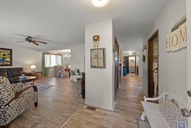 living room with ceiling fan with notable chandelier and hardwood / wood-style floors