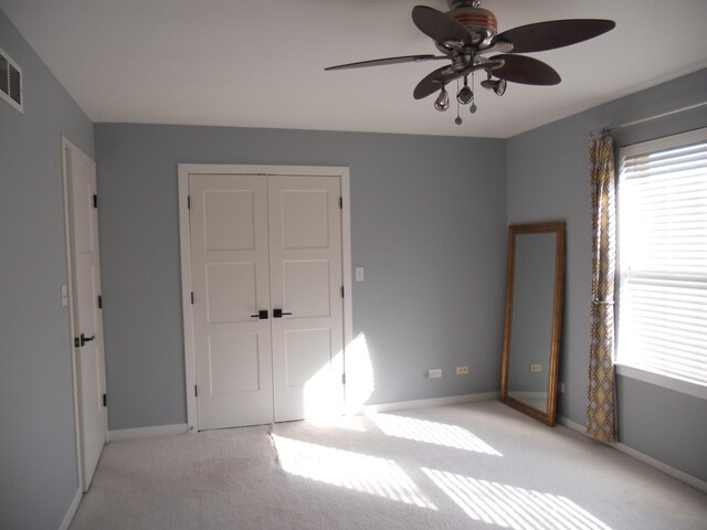 unfurnished bedroom with ceiling fan, light colored carpet, and a closet