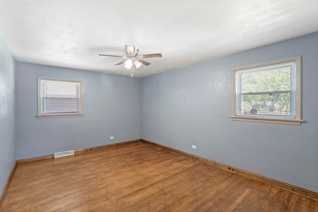 spare room with ceiling fan, a wealth of natural light, and light hardwood / wood-style floors