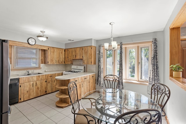 kitchen with white gas range, tasteful backsplash, black dishwasher, sink, and hanging light fixtures