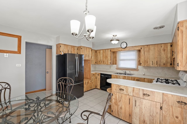 kitchen with sink, gas range gas stove, decorative light fixtures, stainless steel refrigerator, and black dishwasher