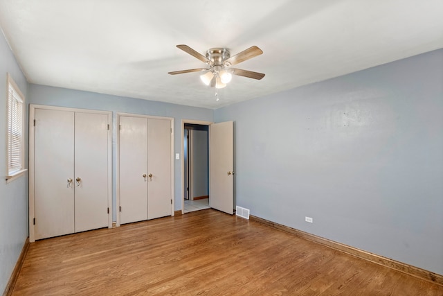 unfurnished bedroom featuring multiple closets, light hardwood / wood-style flooring, and ceiling fan