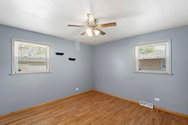 empty room featuring a healthy amount of sunlight, ceiling fan, and light hardwood / wood-style flooring