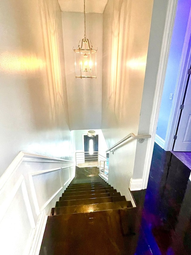 stairway with hardwood / wood-style floors and an inviting chandelier