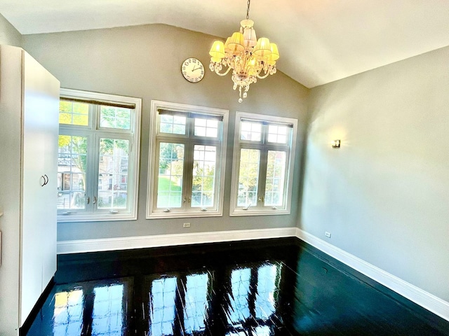 spare room featuring a chandelier, lofted ceiling, and a healthy amount of sunlight