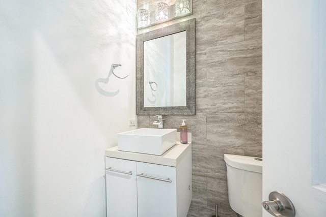 bathroom featuring vanity, tile walls, and toilet