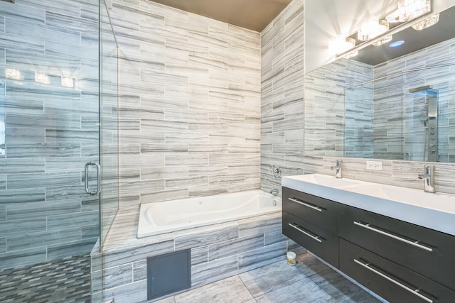 bathroom featuring separate shower and tub, vanity, and tile walls