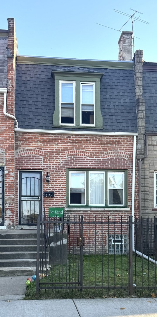 613 E 107th St, Chicago, IL 60628 - view of front of home featuring mansard roof, a fenced front yard, and brick siding