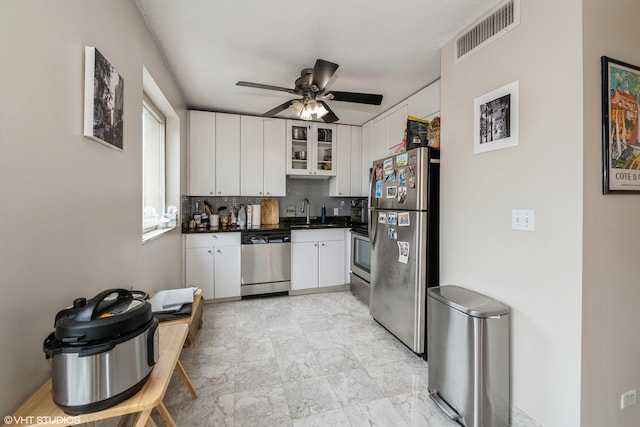 kitchen with ceiling fan, decorative backsplash, stainless steel appliances, sink, and white cabinetry