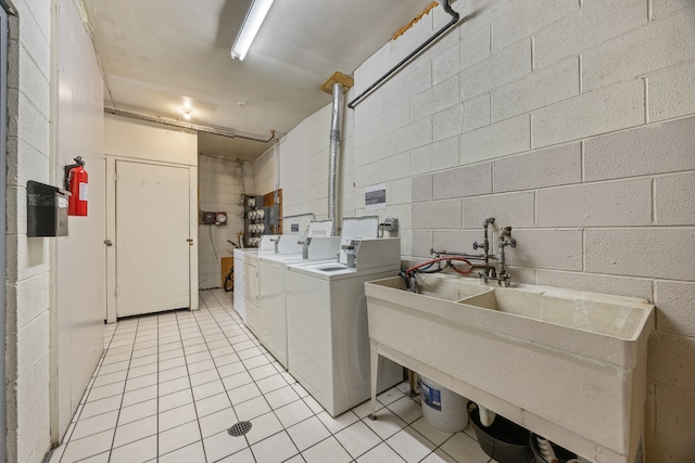 laundry area featuring light tile patterned floors, sink, and separate washer and dryer