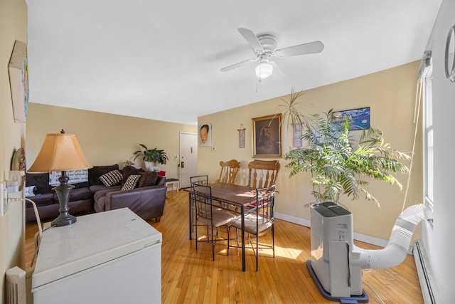 living room with light hardwood / wood-style floors, a baseboard radiator, and ceiling fan