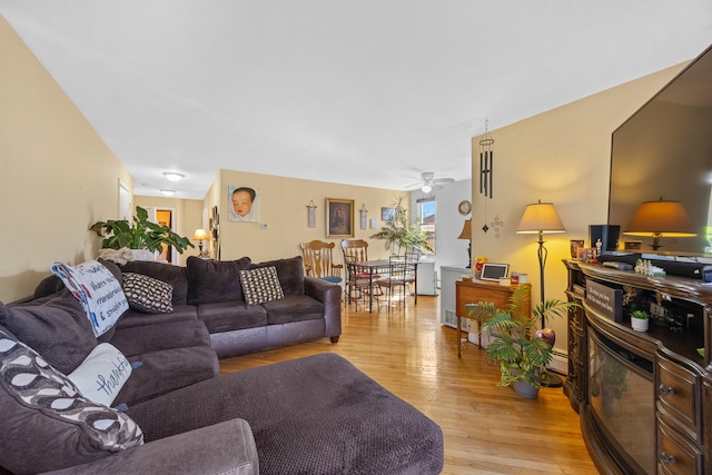 living room with light hardwood / wood-style floors, baseboard heating, and ceiling fan