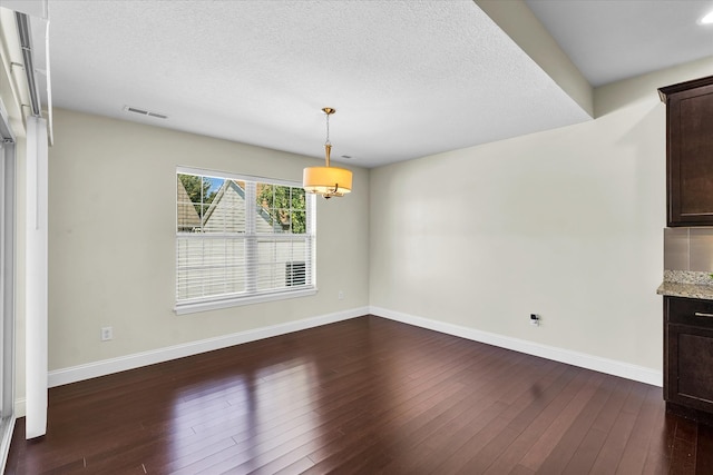 unfurnished dining area with dark hardwood / wood-style floors and a textured ceiling