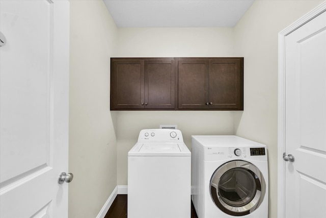 clothes washing area featuring washing machine and dryer, cabinets, and dark hardwood / wood-style flooring