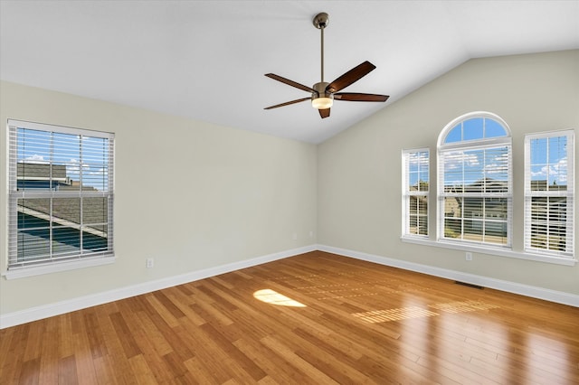 empty room featuring lofted ceiling, a healthy amount of sunlight, ceiling fan, and wood-type flooring