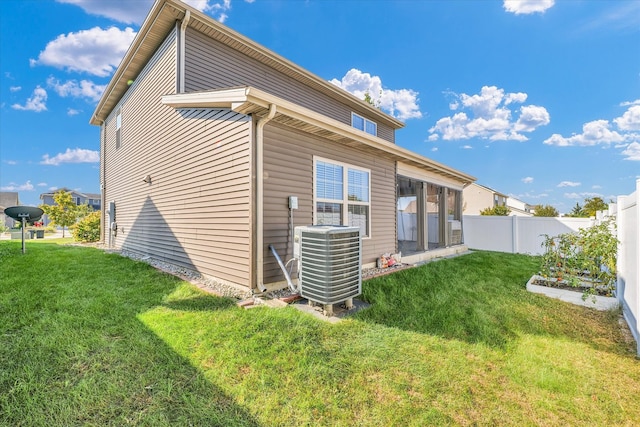 back of property featuring central AC unit and a lawn